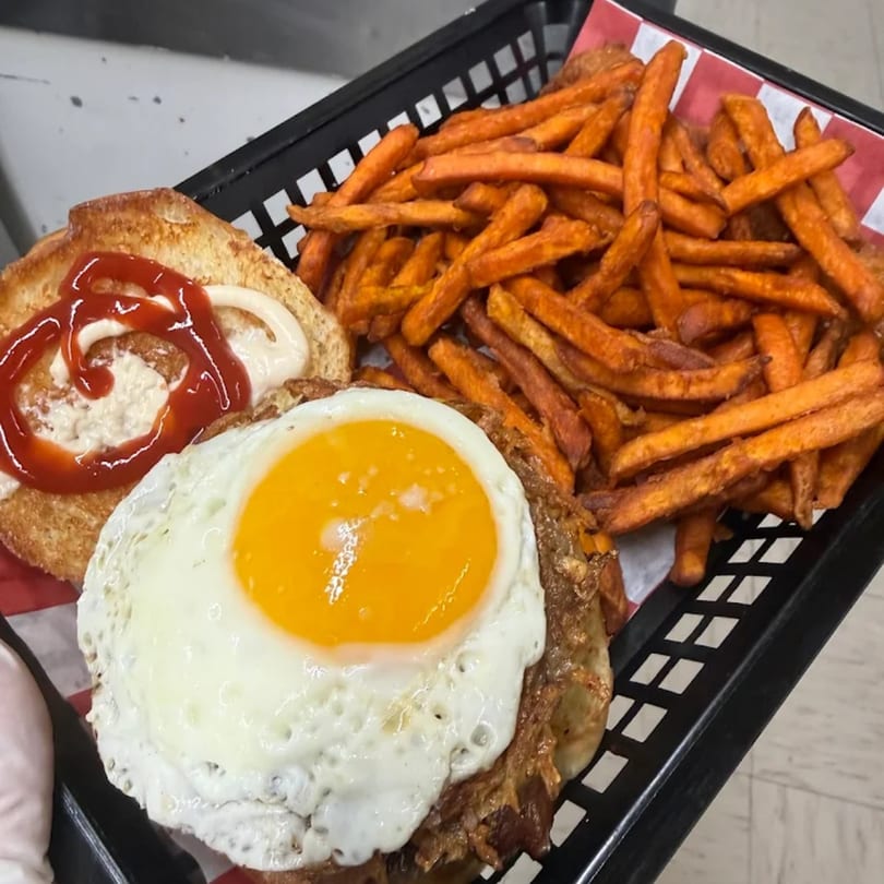 Bergstrom's burger with a fried egg, ketchup, mayonnaise, and a side of sweet potato fries.